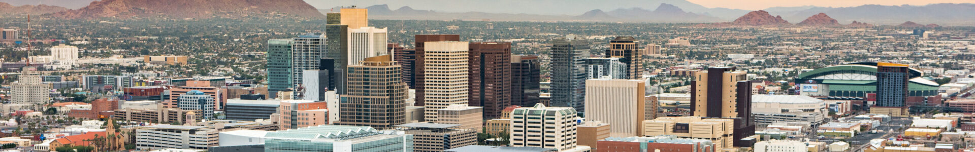Panoramic aerial view of the Phoenix, Arizona skyline against the day's blue sky.
